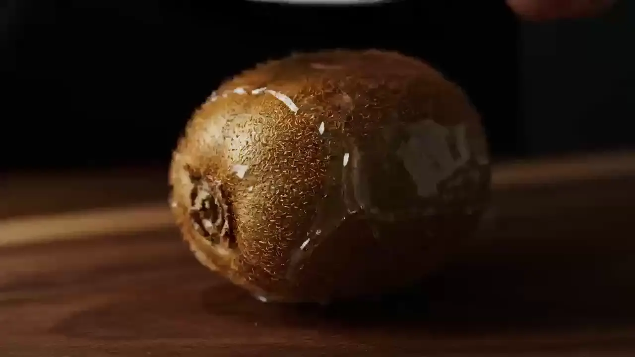Kiwi fruit with a glossy glass-like shell resting on a dark wooden board, from the kiwi template prompt