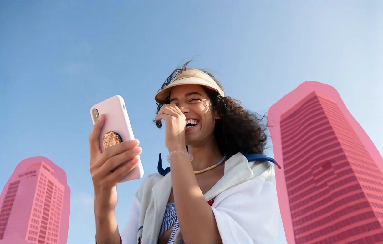 Photo of a woman holding a phone, with two background buildings highlighted in pink for removal.